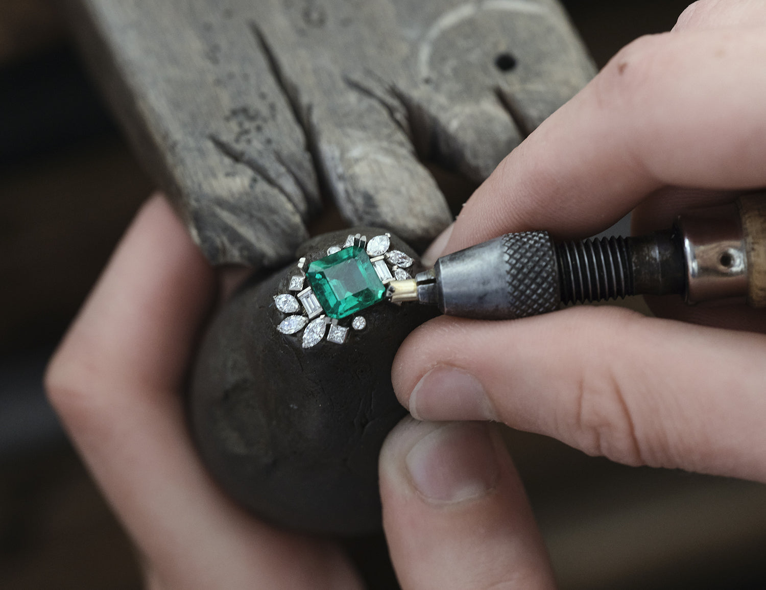 Sertisseur positionne l’émeraude et les diamants sur le bague de fiançailles